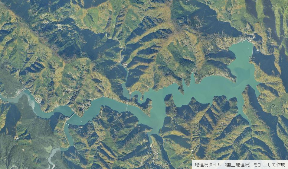 奥多摩湖の空中写真。岸の多くが山の斜面のまま水面へ落ちており、東端に小河内ダムがある