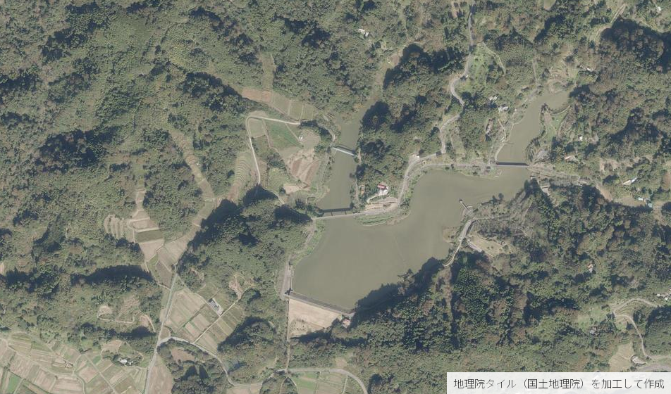 佐久間ダムの空中写真。堤体は草に覆われた斜面で、湖のまわりは森林と段々畑になっている